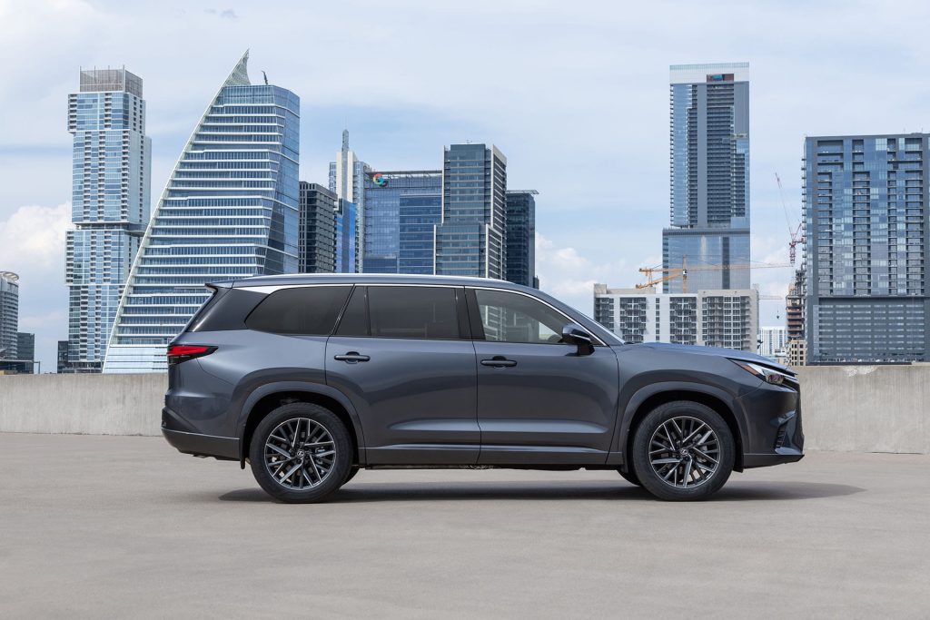 Dark gray Lexus TX 350 Ultra Luxury SUV in side profile parked on a rooftop with a modern city skyline in the background.