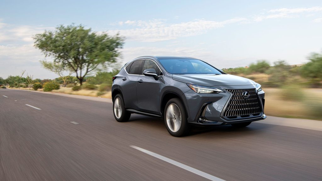 Gray Lexus NX 350h hybrid SUV driving on a suburban road with trees and dry landscape.