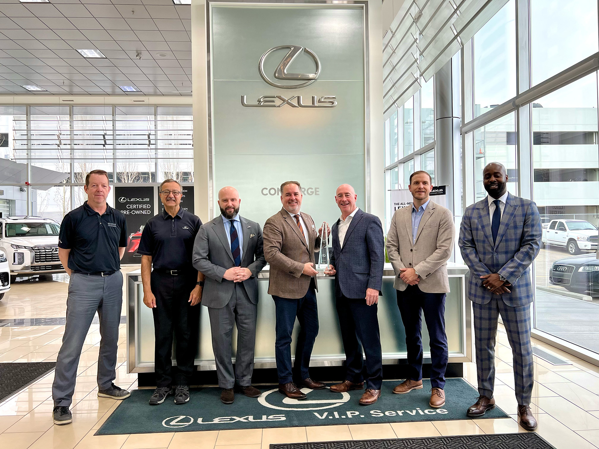 Lexus of Calgary team receiving the Lexus Canada Pursuit of Excellence Award inside the Calgary dealership showroom.